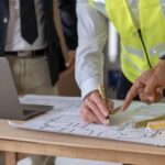Personas revisando planos de construcción en una mesa de trabajo