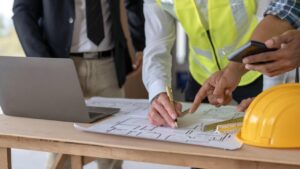 Personas revisando planos de construcci&oacute;n en una mesa de trabajo