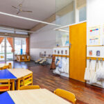 Interior de una escuela con mesas y sillas de colores