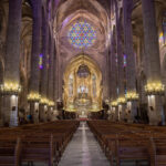 Interior de una iglesia con vitrales coloridos y bancos de madera
