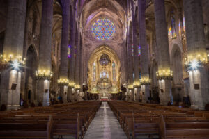 Interior de una iglesia con vitrales coloridos y bancos de madera