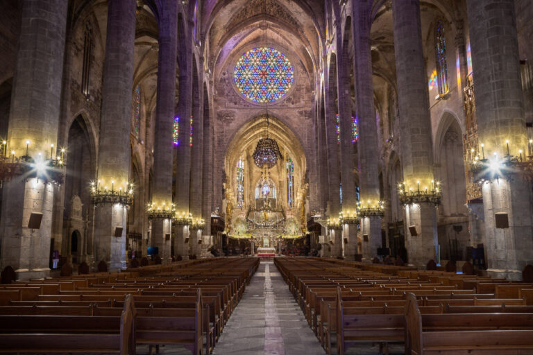 Interior de una iglesia con vitrales coloridos y bancos de madera