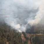 Vista a&eacute;rea de un incendio forestal en Puigpunyent con humo y &aacute;rboles