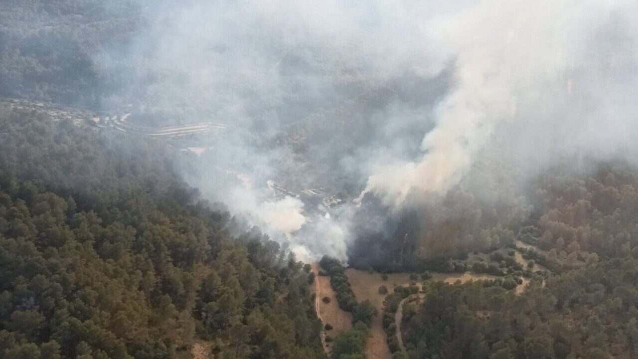 Vista a&eacute;rea de un incendio forestal en Puigpunyent con humo y &aacute;rboles