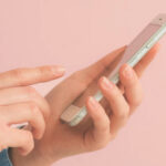 Persona usando un teléfono móvil con fondo rosa