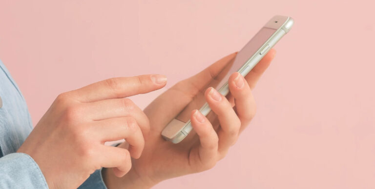 Persona usando un teléfono móvil con fondo rosa