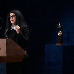 Marjane Satrapi hablando en un evento con banderas de Espa&ntilde;a y Asturias