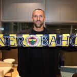 Vedat Muriqi sosteniendo una bufanda del Fenerbah&ccedil;e en una sala