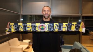 Vedat Muriqi sosteniendo una bufanda del Fenerbah&ccedil;e en una sala