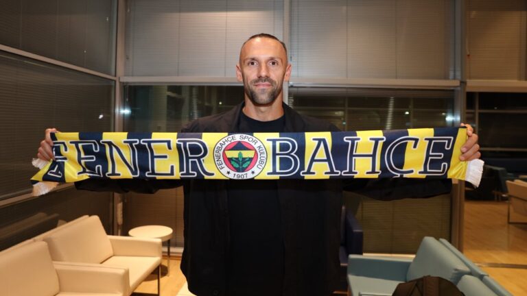 Vedat Muriqi sosteniendo una bufanda del Fenerbah&ccedil;e en una sala