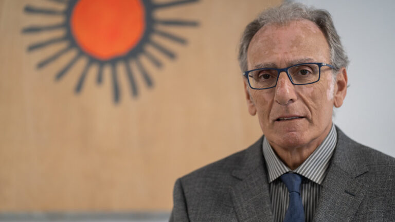 Retrato de un hombre con gafas en un fondo artístico.