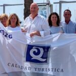 Grupo de personas sosteniendo la bandera de calidad turística en Alcudiamar