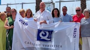Grupo de personas sosteniendo la bandera de calidad tur&iacute;stica en Alcudiamar