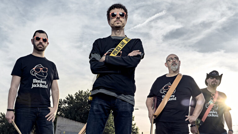 Miembros de la banda Monkey Jack Band posando con camisetas y gafas de sol