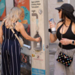 Turistas llenando botellas de agua en una fuente pública