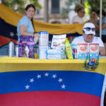 Mesa con productos de ayuda humanitaria y bandera de Venezuela en Palma.