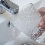 Grifo de agua vertiendo en un vaso transparente