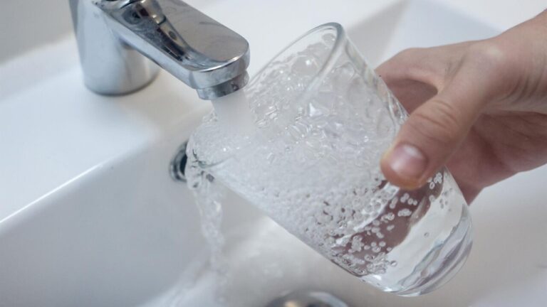 Grifo de agua vertiendo en un vaso transparente