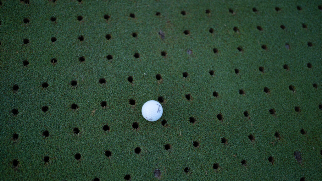 Vista de un green de golf con agujeros de aireación y una bola de golf