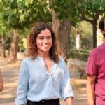 Tres candidatos socialistas caminando en un parque con árboles