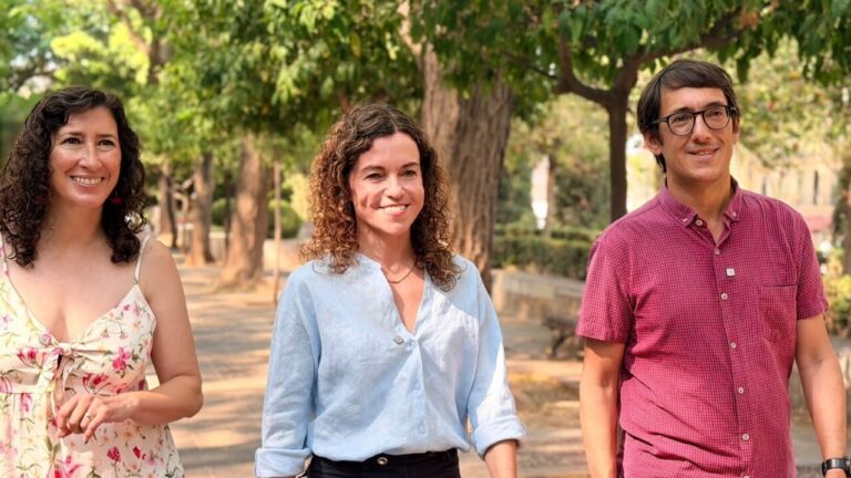 Tres candidatos socialistas caminando en un parque con árboles