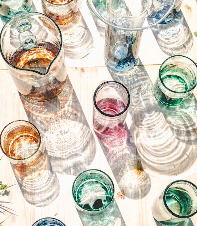 Vasos de diferentes colores y formas sobre una mesa iluminada