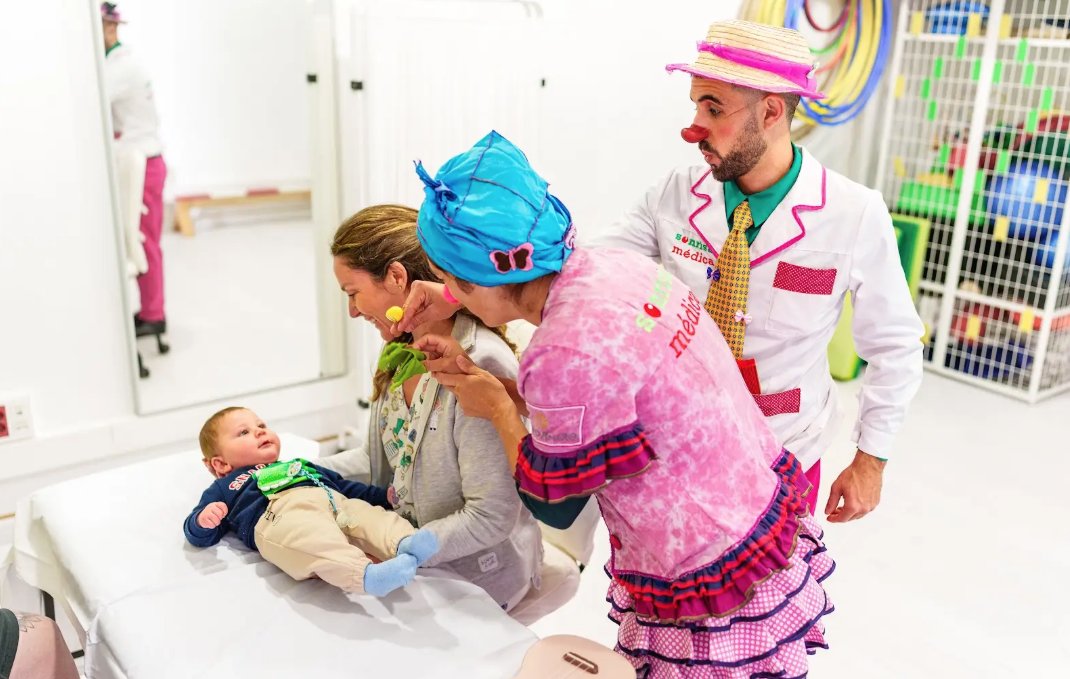 Clown interacting with a baby and mother in a hospital setting