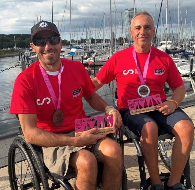 Dos deportistas en silla de ruedas con medallas en un puerto