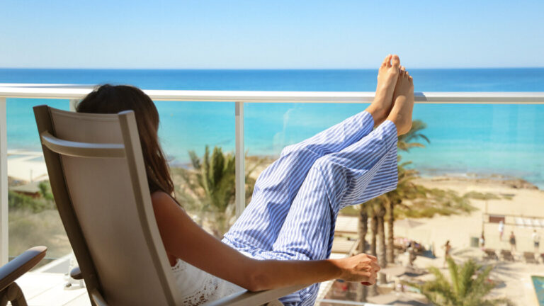 Mujer relaj&aacute;ndose en un balc&oacute;n con vista al mar en el Hotel Riu Palace La Mola