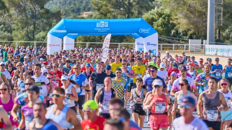 Corredores participando en la Half Marathon Magaluf bajo un arco de meta