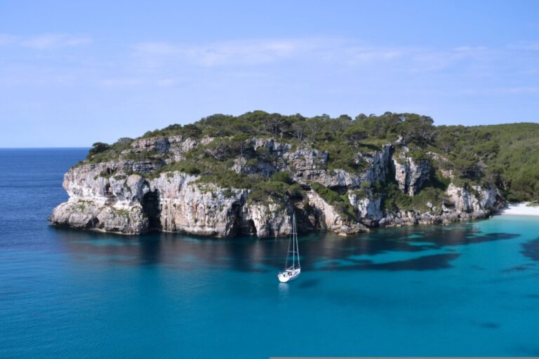 Vista de una isla balear con agua turquesa y un barco