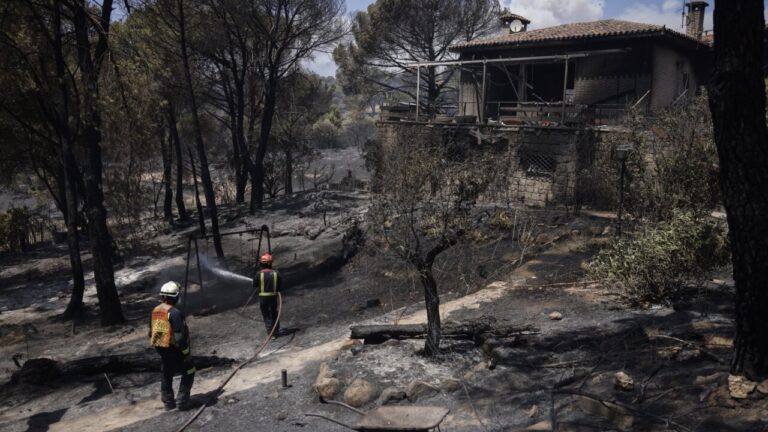 Bomberos trabajando en un incendio forestal cerca de una casa en Madrid