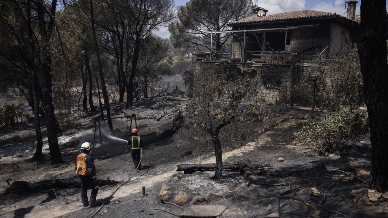 Bomberos trabajando en un incendio forestal cerca de una casa en Madrid