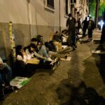 Grupo de inmigrantes sentados en la calle esperando ayuda
