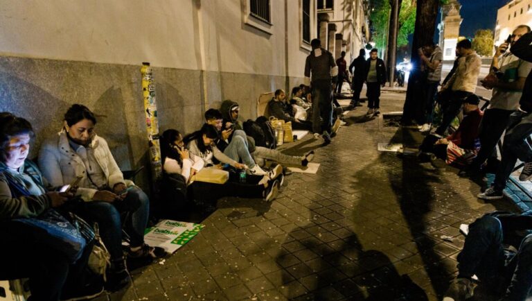 Grupo de inmigrantes sentados en la calle esperando ayuda