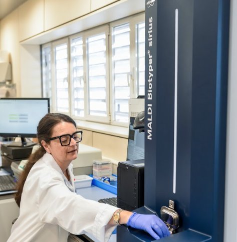 Mujer en laboratorio usando tecnología MALDI-TOF para identificar microorganismos