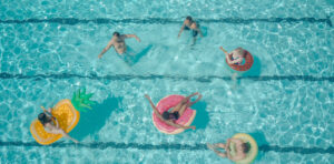 Personas disfrutando en una piscina con flotadores de frutas