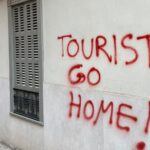 Pintadas en la pared que dicen Tourist Go Home en rojo