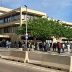 Edificio de administración con personas haciendo fila para regularización de extranjeros
