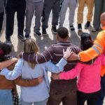 Grupo de personas abrazadas en un círculo durante una actividad de apoyo