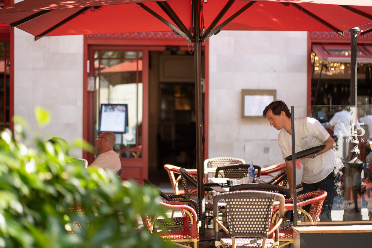 Camarero limpiando mesas en una terraza de cafeter&iacute;a