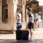 Dos hombres conversando en la calle con maletas en mano