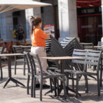 Trabajadora organizando sillas en una terraza al aire libre