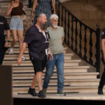 Dos hombres caminando por escaleras con polic&iacute;as en el fondo