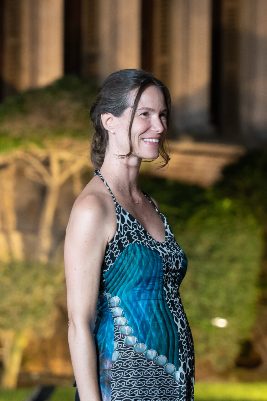 Mujer sonriente en un evento al aire libre con vestido colorido