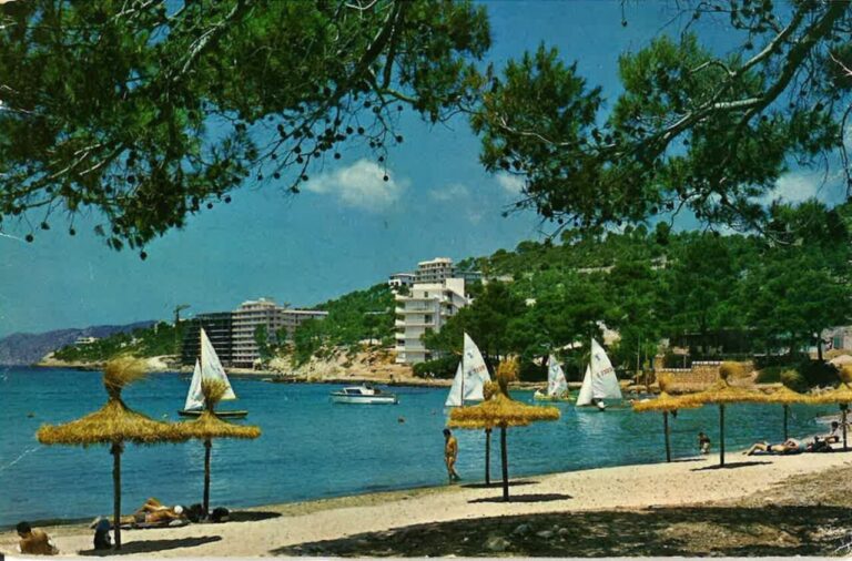 Playa de Calvià con sombrillas y barcos en el agua
