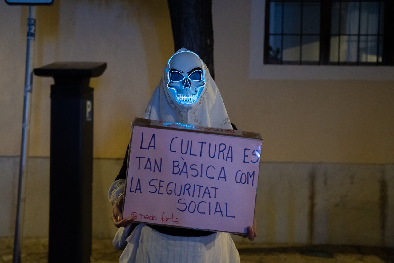 Persona con máscara de calavera sosteniendo un cartel sobre la cultura