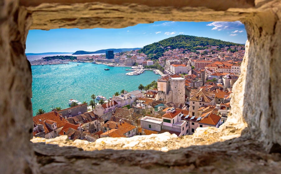 Vista panor&aacute;mica de una ciudad costera con mar y monta&ntilde;as al fondo