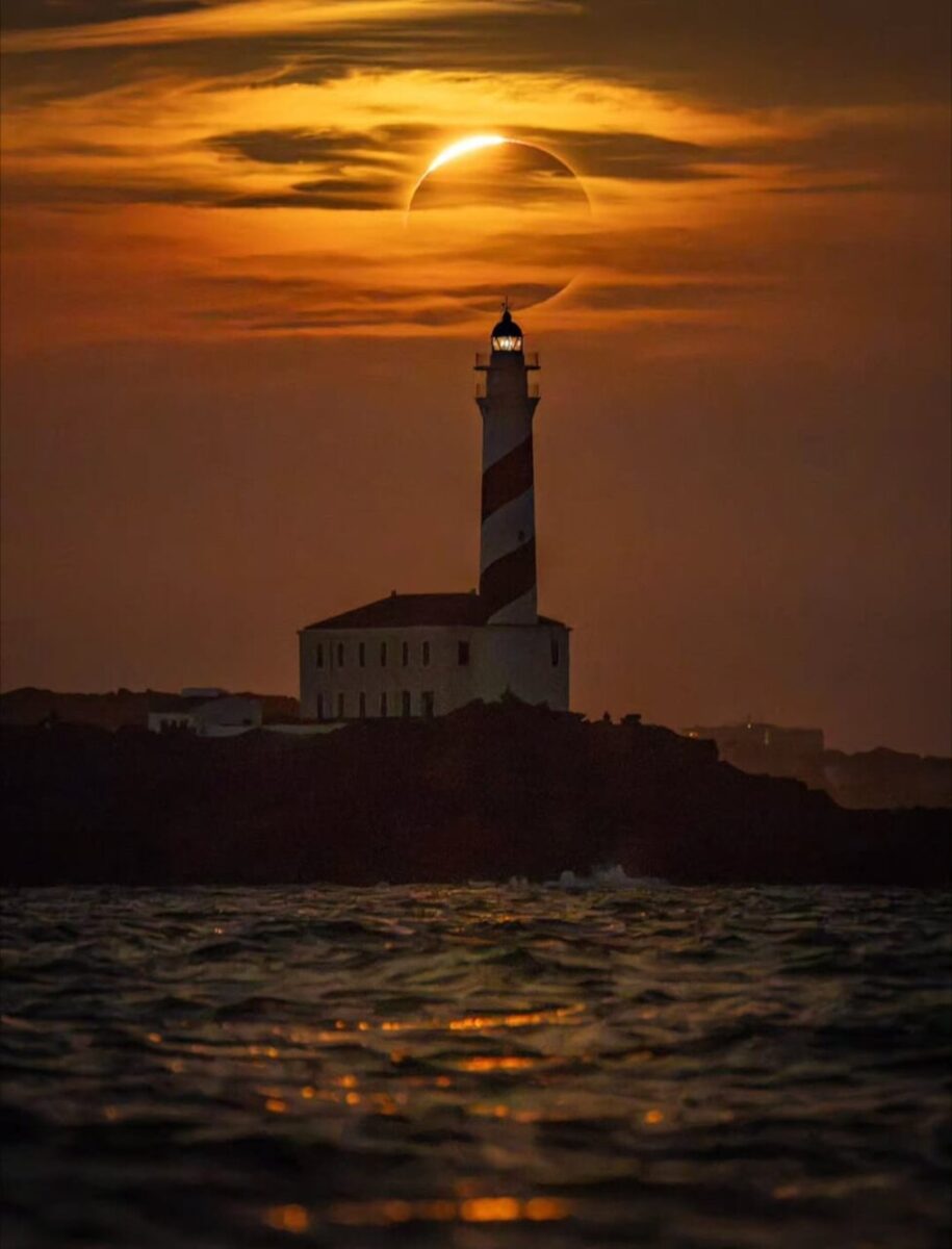 Eclipse total de sol detr&aacute;s de un faro en Mallorca durante el atardecer