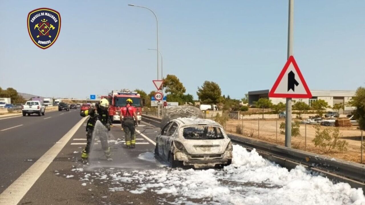 Bomberos apagando un coche en llamas en la autopista Ma-13